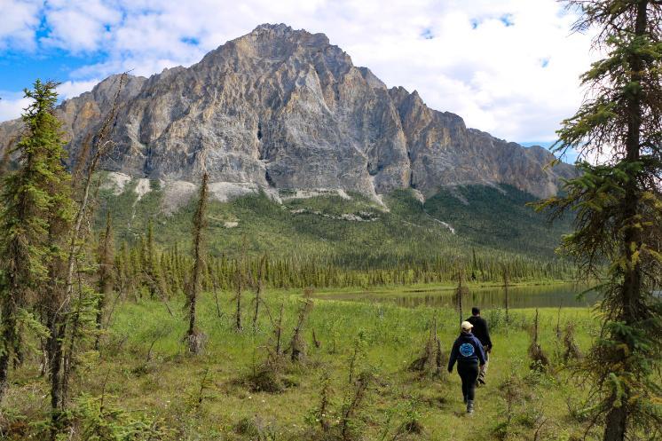 Two students in Alaska walking with a mountain in the background