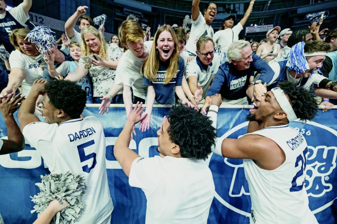 Basketball players greet fans after a game