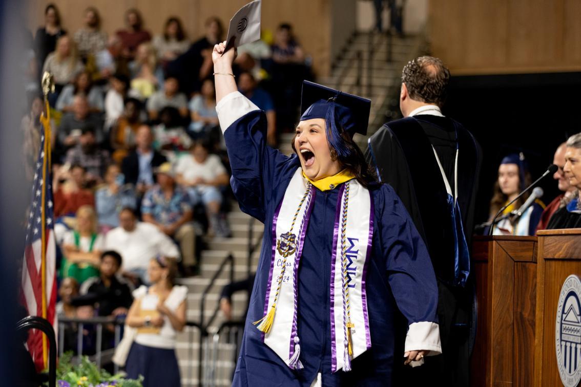 Excited student crossing the stage during Commencement